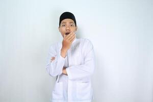 conmocionado musulmán asiático hombre aislado en blanco antecedentes cubierta su boca con doblada brazo foto