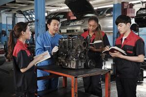 Specialist lecture, a male supervisor engineer train and describe automotive engines with mechanic worker staff teams for repair work at car service garage and maintenance jobs in automobile industry. photo