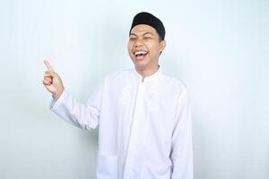 laughing asian muslim man pointing side isolated on white background photo