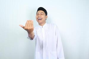 excited asian muslim man show inviting gesture with laugh isolated on white background photo