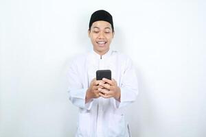 happy asian muslim man smiling while looking at his phone photo