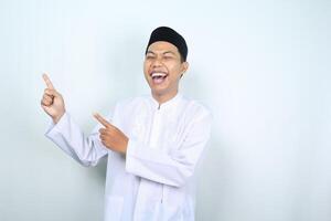 laughing asian muslim man pointing side isolated on white background photo