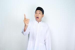 muslim asian man pointing beside with shocked expression isolated on white background, looking at camera photo