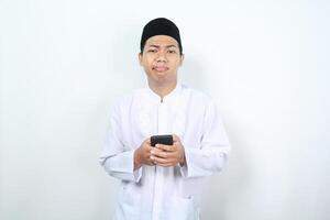 stressed asian muslim man show disappointed expression while texting with his phone isolated photo