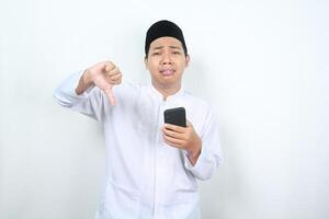 disappointed muslim asian man giving thumb down with holding phone photo