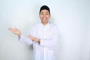 atractivo musulmán asiático hombre presentación mano a el Derecha lado con sonriente cara aislado en blanco fondo, mirando a cámara foto