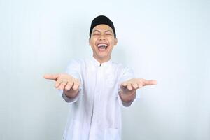 portrait of laughing asian muslim man presenting arm forward to camera isolated on white background photo