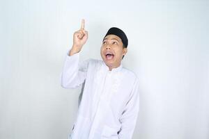 surprised asian muslim man pointing to above isolated on white background photo