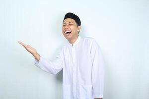 portrait of laughing asian muslim man presenting to side isolated on white background photo