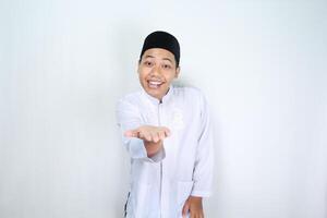 funny asian muslim man with surprised expression presenting hand forward to camera isolated on white background photo