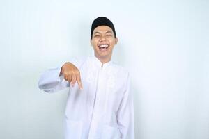 laughing asian muslim man pointing down isolated on white background photo