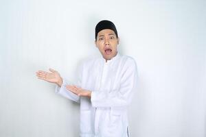 asian man muslim raising palm presenting to beside with shocked face expression isolated on white background photo