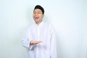portrait of laughing asian muslim man presenting to the middle isolated on white background photo