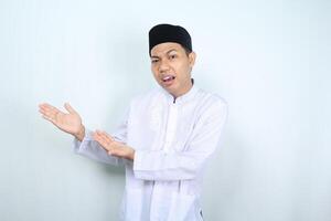 confused asian muslim man presenting to empty side isolated on white backround photo