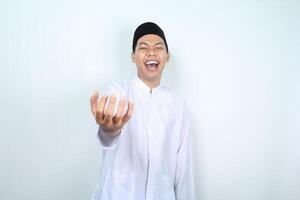 asian muslim man holding imaginary bowl with empty palm and laughing expression isolated on white background photo