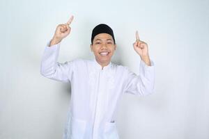 happy muslim asian man pointing up isolated on white background photo