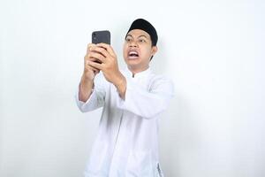 asian muslim man show angry expression while texting with his phone photo