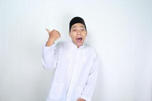 funny asian muslim man giving thumbs up with surprised expression isolated on white background photo