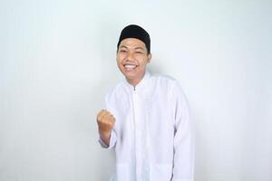 happy muslim asian man raising fist show victory gesture in eid mubarak celebration isolated on white background photo