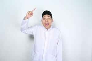 surprised asian muslim man pointing to above isolated on white background photo