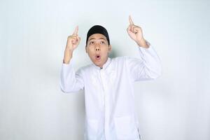 shocked asian muslim man pointing to above isolated on white background photo