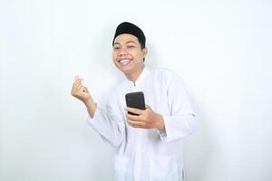 smiling asian muslim man showing korean love signs with holding mobile phone isolated photo