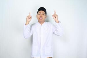 stressed muslim man asian pointing to above with sad expresseion isolated on white background photo