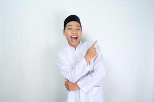 attractive muslim asian man pointing to the left side and shouting with mouth open isolated on white background photo