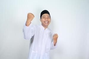 happy muslim asian man raising fist show victory gesture in eid mubarak celebration isolated on white background photo