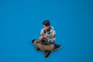 a student is sitting holding a smartphone on a skateboard with a blue background photo