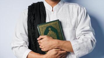 Muslim man is carrying the Koran with both hands. ramadan month conceptMuslim man is carrying the Al-Quran with both hands. ramadan month concept photo