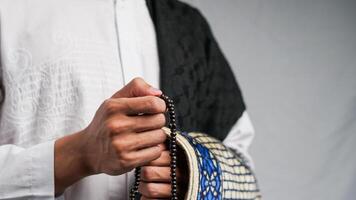 man is praying with prayer beads and carrying a prayer mat photo