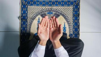 parte superior ver de hombre musulmán con Orando mano en el oración estera foto