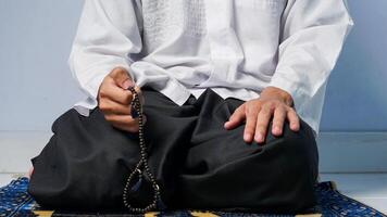 Close up of muslim man praying on prayer mat and doing last movement on prayer procedure photo