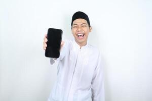 happy asian muslim man showing blank phone screen with laugh photo