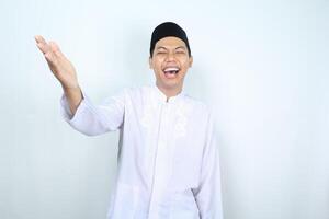 portrait of laughing asian muslim man presenting arm forward to camera isolated on white background photo