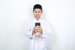 asiático musulmán hombre espectáculo enojado expresión mientras mirando a su teléfono foto