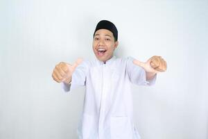 funny asian muslim man giving thumbs up with surprised expression isolated on white background photo