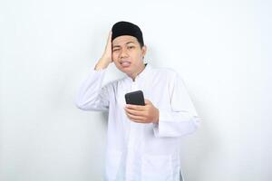 muslim asian man holding phone with touching his head feeling dizzy isolated photo