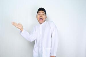 funny asian muslim man with surprised expression presenting hand to beside isolated on white background photo