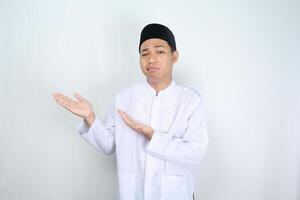 stressed asian muslim man looks tired while presenting to side isolated on white background photo