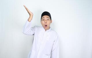 shocked asian man muslim raising hand above to presenting isolated on white background photo