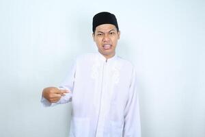 confused asian muslim man pointing to the middle isolated on white background photo