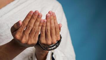 Muslim man wearing ihram clothes is praying with prayer beads in his hands photo