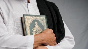 man holding the Quran with prayer beads in his hand photo