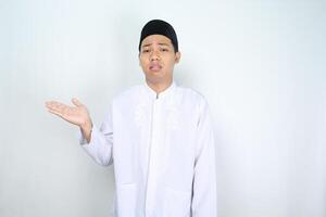 stressed asian muslim man looks tired while presenting to side isolated on white background photo