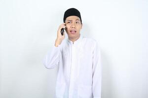 asiático musulmán hombre hablando en el teléfono espectáculo confuso expresión aislado en blanco antecedentes foto