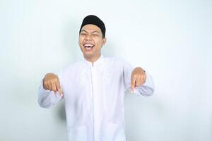 laughing asian muslim man pointing down isolated on white background photo