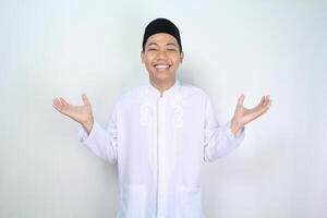 smiling asian muslim man raising hands show empty palm holding imaginary food plate isolated on white background photo