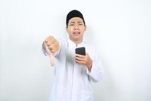 disappointed muslim asian man giving thumb down with holding phone photo